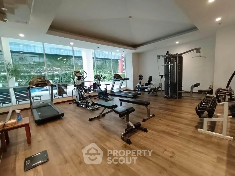 Spacious modern gym with state-of-the-art equipment and large windows offering natural light.