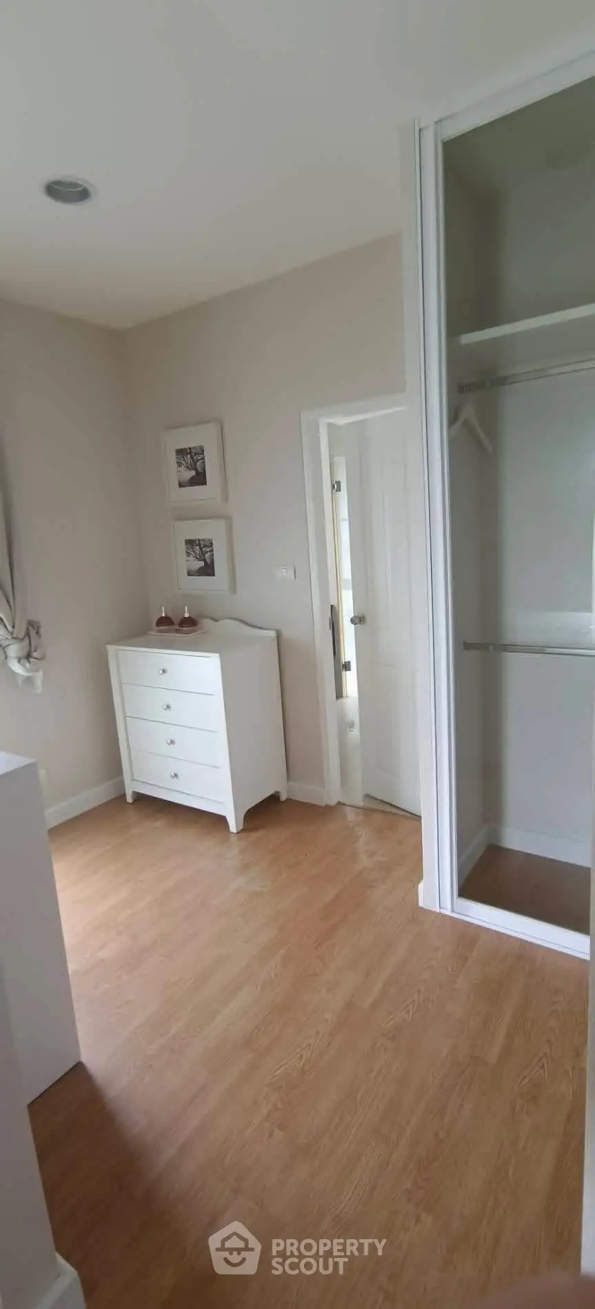 Spacious bedroom with wooden flooring and built-in closet
