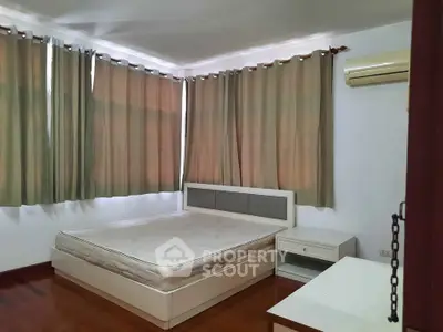 Spacious bedroom with large windows and air conditioning in modern apartment.