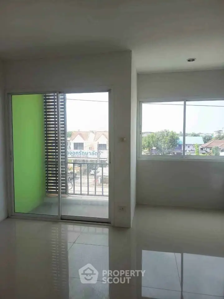 Spacious apartment with large windows and balcony offering natural light and urban views.