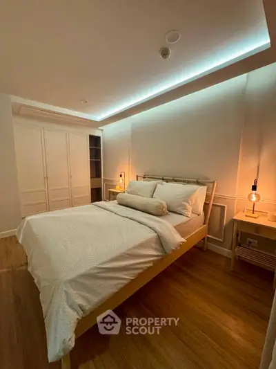 Cozy bedroom with modern lighting and wooden flooring, featuring a comfortable bed and spacious wardrobe.