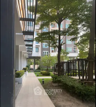 Modern apartment building with lush garden and pathway, perfect for urban living.
