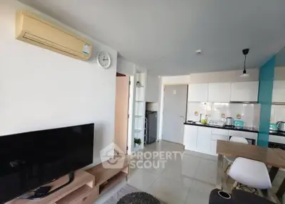 Modern living room with sleek kitchen and dining area, featuring stylish furniture and appliances.