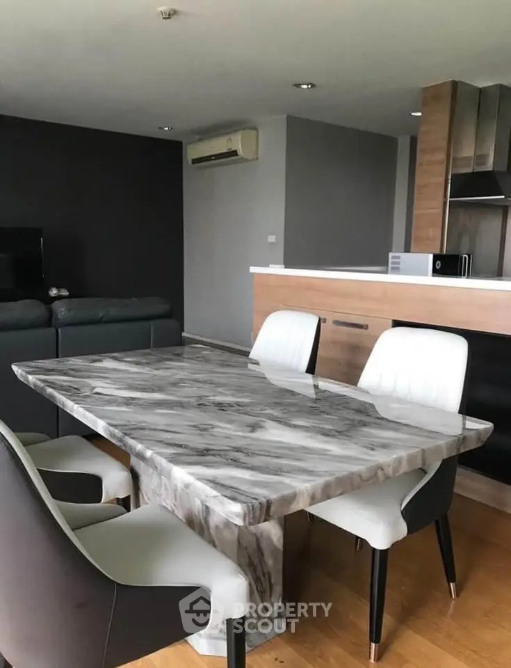 Modern dining area with marble table and stylish chairs in open-plan living space.