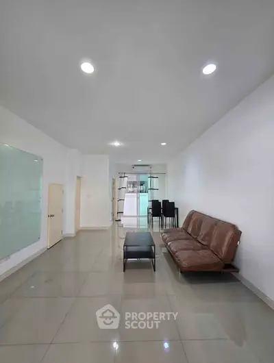 Spacious modern living room with sleek tile flooring and minimalist furniture.