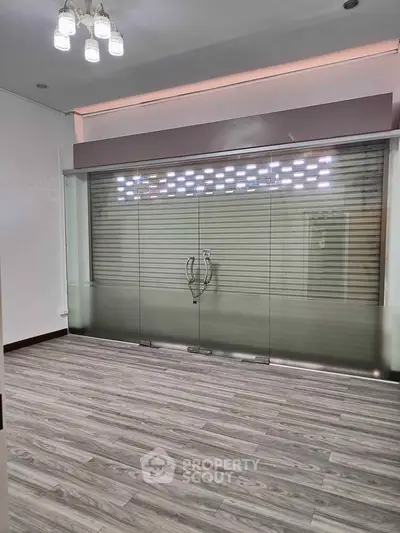 Spacious room with modern glass doors and elegant flooring, ideal for versatile use.