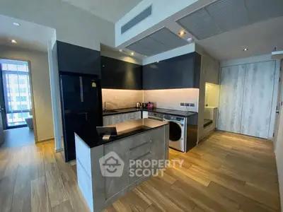 Modern kitchen with sleek black cabinets and integrated appliances in a stylish apartment.