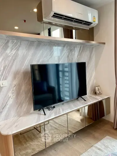 Modern living room with sleek TV setup and air conditioning, featuring elegant marble accents and stylish decor.