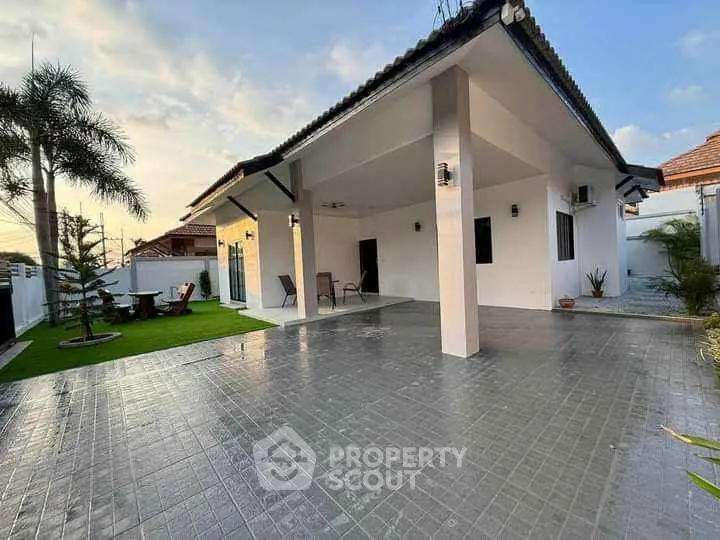 Spacious modern house exterior with tiled patio and lush garden, perfect for outdoor living.