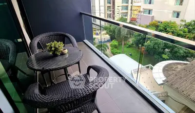 Stylish balcony with wicker furniture and scenic view of lush greenery in modern apartment.