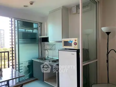 Modern compact kitchen with balcony view in urban apartment