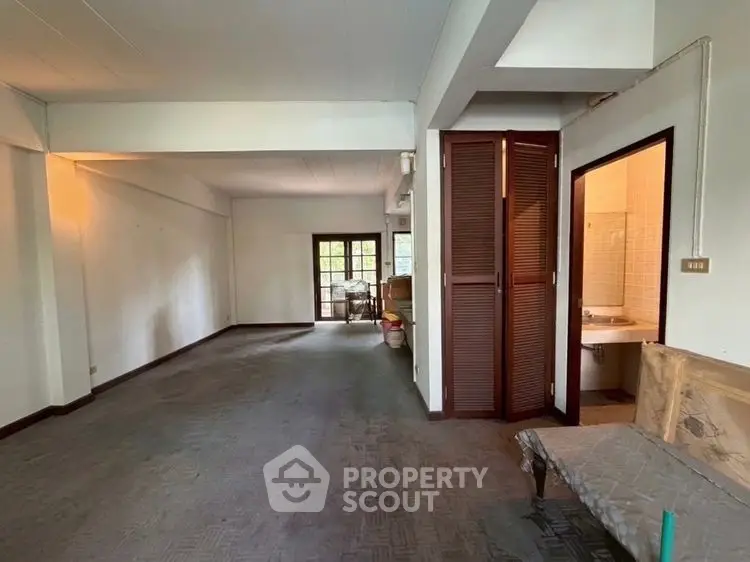 Spacious open-plan living area with natural light and adjacent bathroom, ideal for customization.