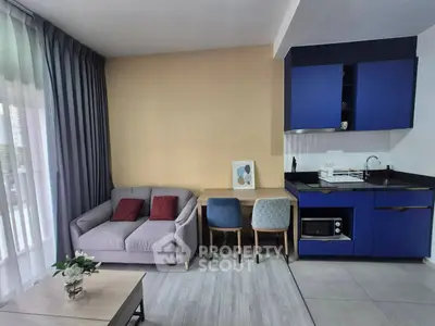 Modern living room with stylish blue kitchen cabinets and cozy seating area, perfect for urban living.