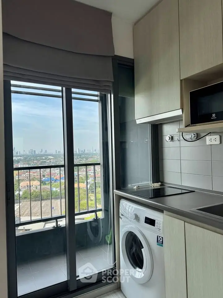 Modern kitchen with washing machine and city view from balcony.