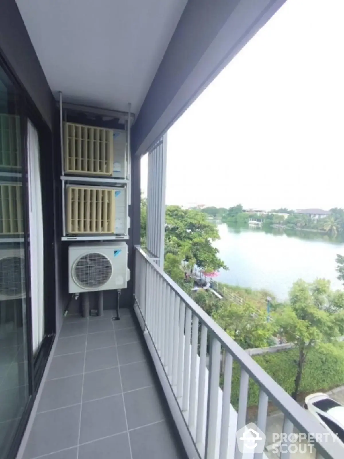 Modern balcony with serene lake view and air conditioning units