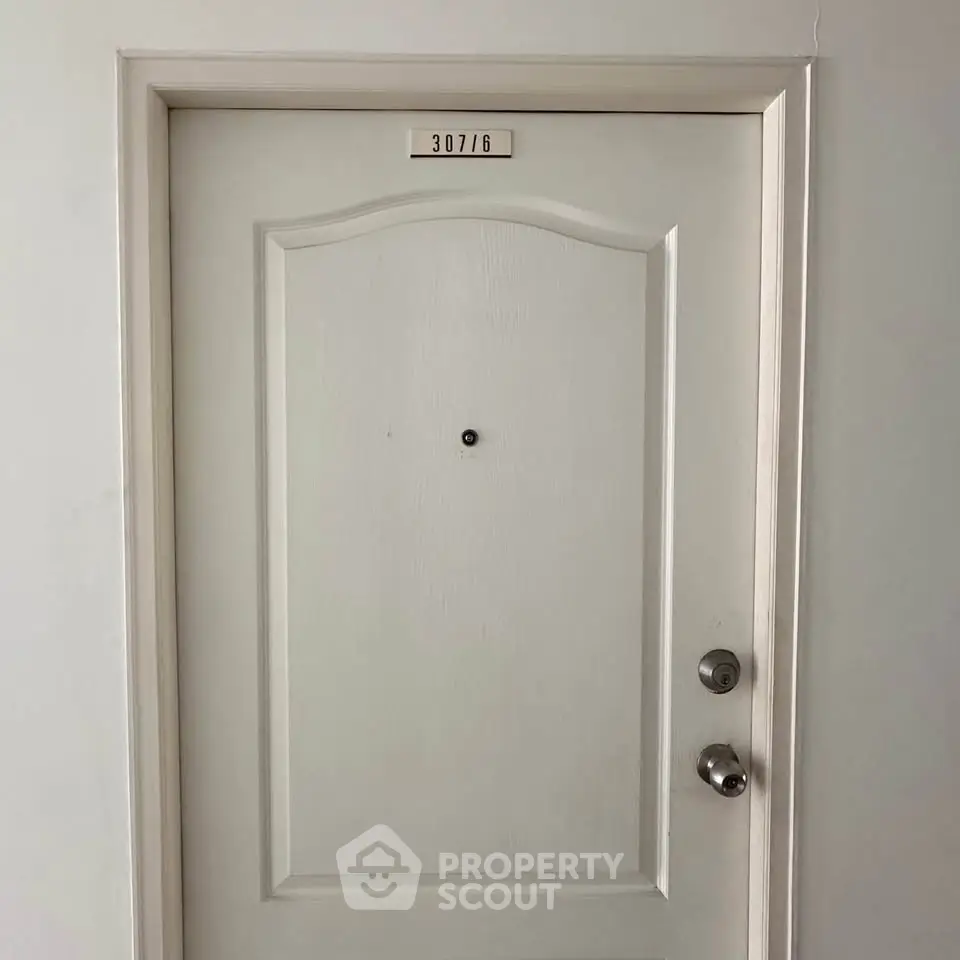 Modern apartment door with peephole and room number 307/6, showcasing secure entry.
