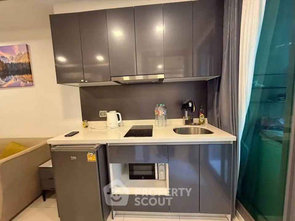 Modern compact kitchen with sleek cabinets and built-in appliances in a cozy apartment.