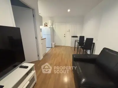 Modern living room with sleek black leather sofa and open kitchen layout in cozy apartment.