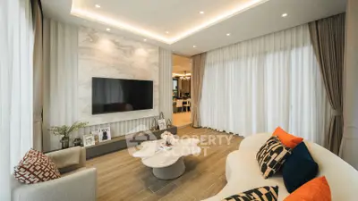 Luxurious modern living room with elegant decor and stylish furniture, featuring a large TV and marble accent wall.