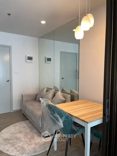 Modern living room with cozy sofa and dining table, featuring stylish lighting and mirrored wall.