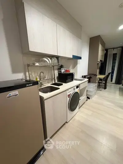 Modern kitchen with sleek cabinetry, compact appliances, and stylish flooring in a contemporary apartment.