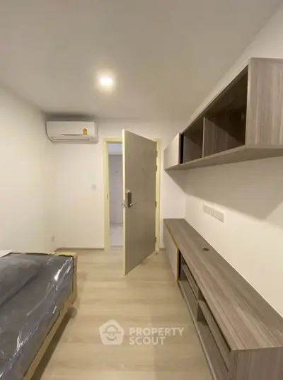 Modern bedroom with sleek wooden furniture and air conditioning unit.