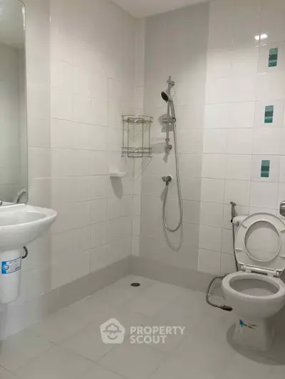 Spacious bathroom with modern shower and toilet in a tiled setting.