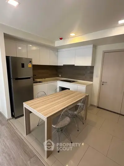 Modern kitchen with sleek design, featuring stainless steel fridge and stylish dining area.