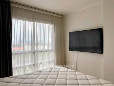 Modern bedroom with large window and wall-mounted TV, offering a bright and airy atmosphere.