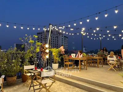 Chic rooftop dining area with string lights and city views, perfect for evening gatherings.