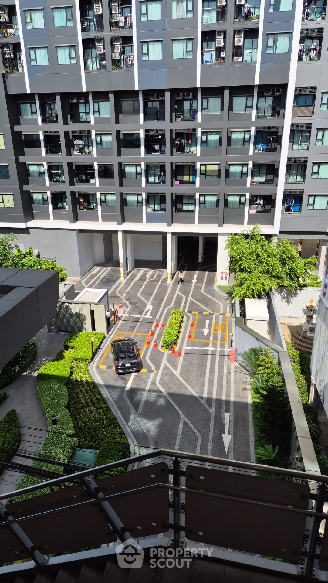 Modern urban building exterior with landscaped entrance and parking area