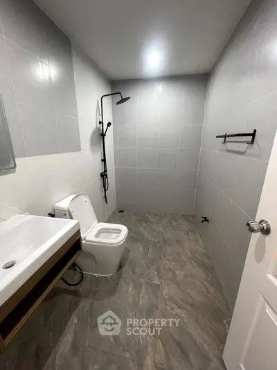 Modern bathroom with sleek fixtures and minimalist design, featuring a spacious shower area.