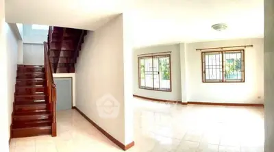 Spacious bright living area with elegant wooden staircase and large windows