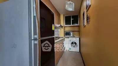 Modern kitchen with fridge, washing machine, and microwave in compact layout.