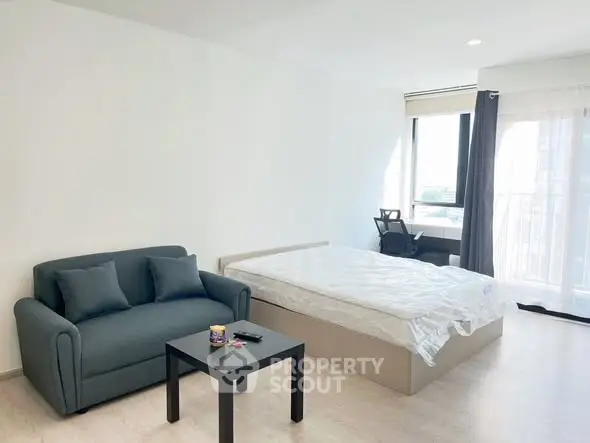 Spacious bedroom with modern furnishings and large window offering natural light.