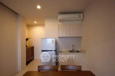Modern kitchen with compact fridge and sleek cabinetry in cozy apartment.