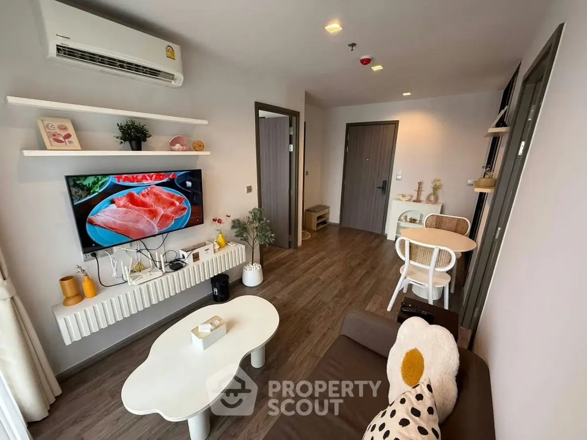 Modern living room with stylish decor and wall-mounted TV in cozy apartment.