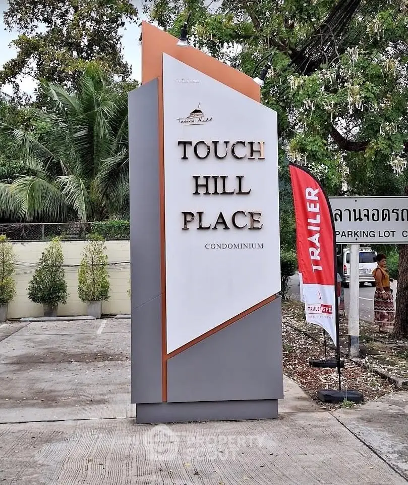 Touch Hill Place Condominium entrance sign with lush greenery and modern design.