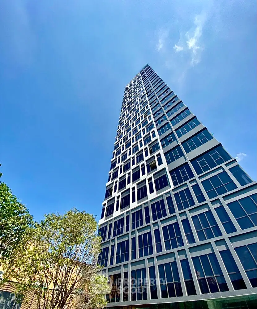 Stunning modern high-rise building with sleek glass facade against a clear blue sky.