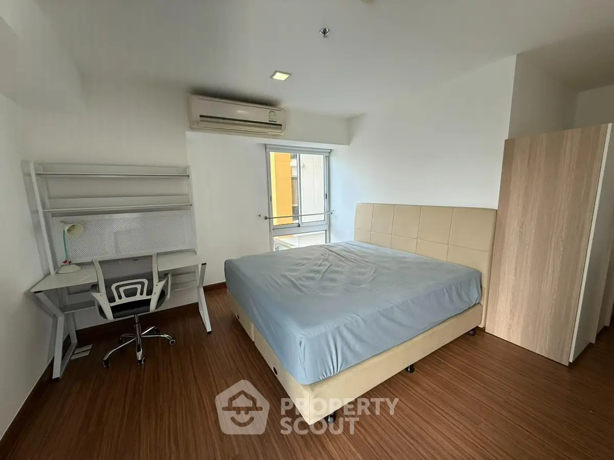 Modern bedroom with sleek furniture and natural light, featuring a comfortable bed and study desk.