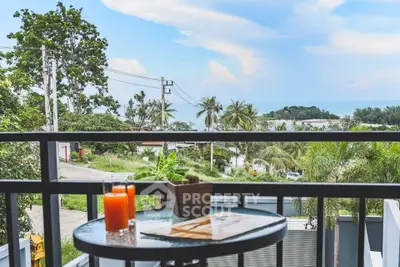 Stunning balcony view with lush greenery and ocean in the background, perfect for relaxation.