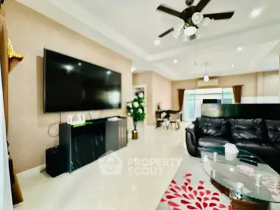 Spacious living room with modern decor and large TV, perfect for family gatherings.