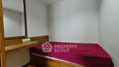 Cozy bedroom with built-in wooden furniture and red bedding, perfect for compact living spaces.