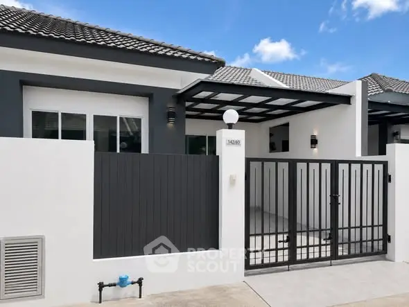Modern single-story house with sleek black and white exterior and gated entrance.