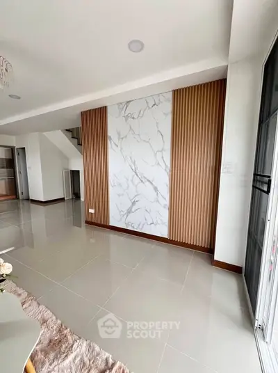 Modern living room with marble accent wall and sleek tile flooring in a stylish home.
