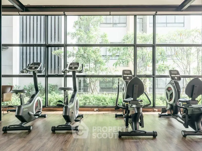 Modern gym with exercise bikes and large windows in a luxury apartment complex.