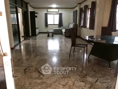 Spacious living room with marble flooring and modern furniture in a well-lit apartment.