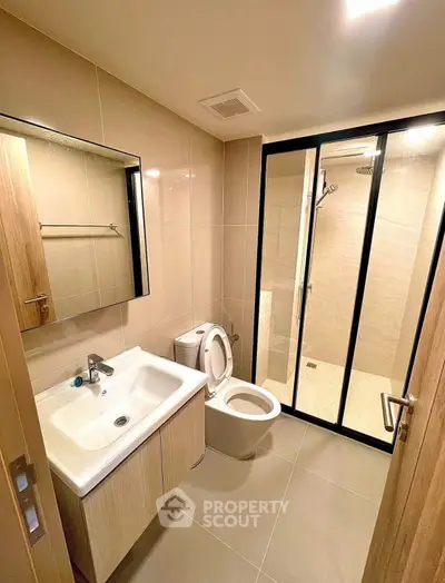 Modern bathroom with glass shower and sleek fixtures in contemporary apartment.