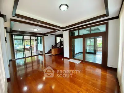 Spacious living room with wooden flooring and large windows for natural light.
