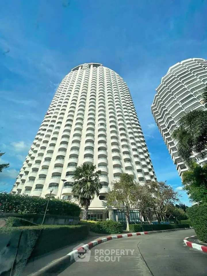 Stunning high-rise building with modern architecture and lush landscaping under a clear blue sky.
